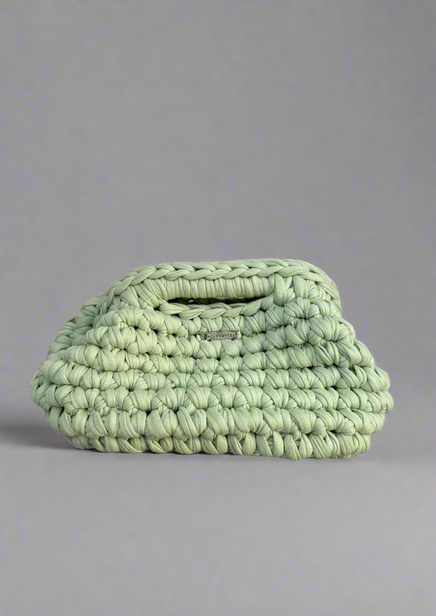 Light green woven clutch bag on a gray background