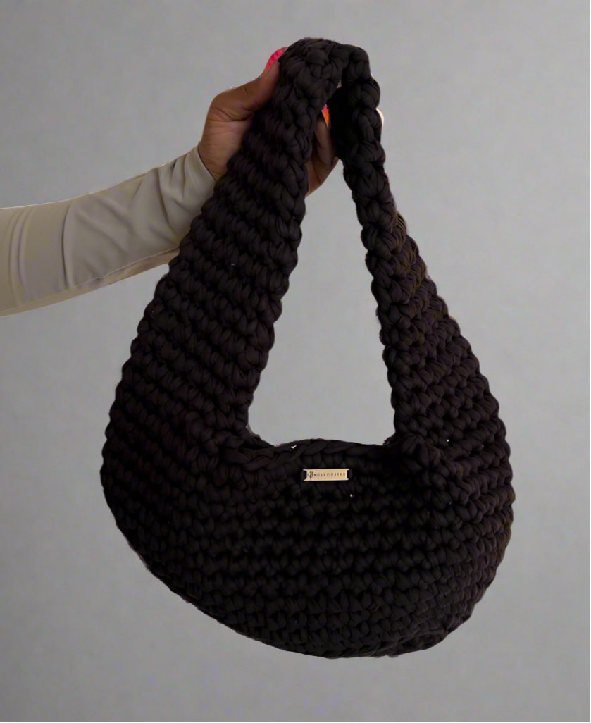 brown crochet handbag held by a person against a white background