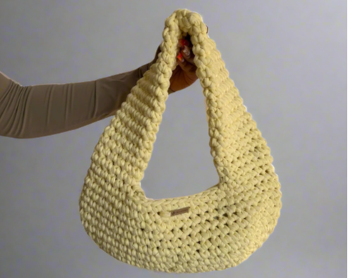 yellow crochet bag held by a person on a white background
